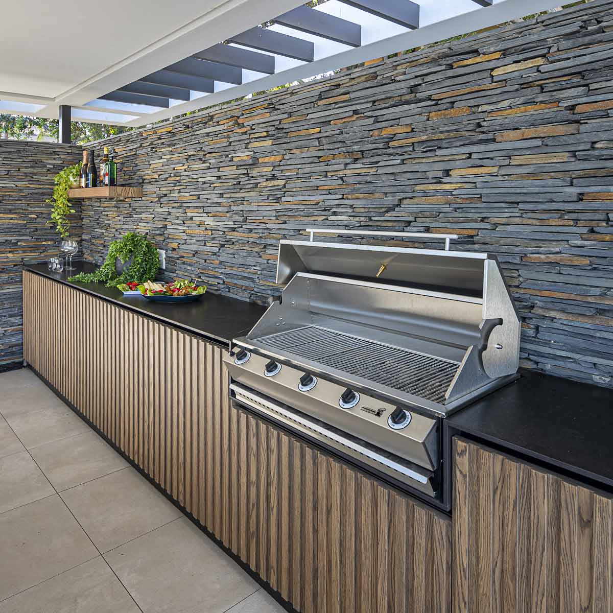 Chad-O-Chef Sizzler braai outdoors with grilling tools and food, showcasing a premium braai setup for outdoor cooking.
