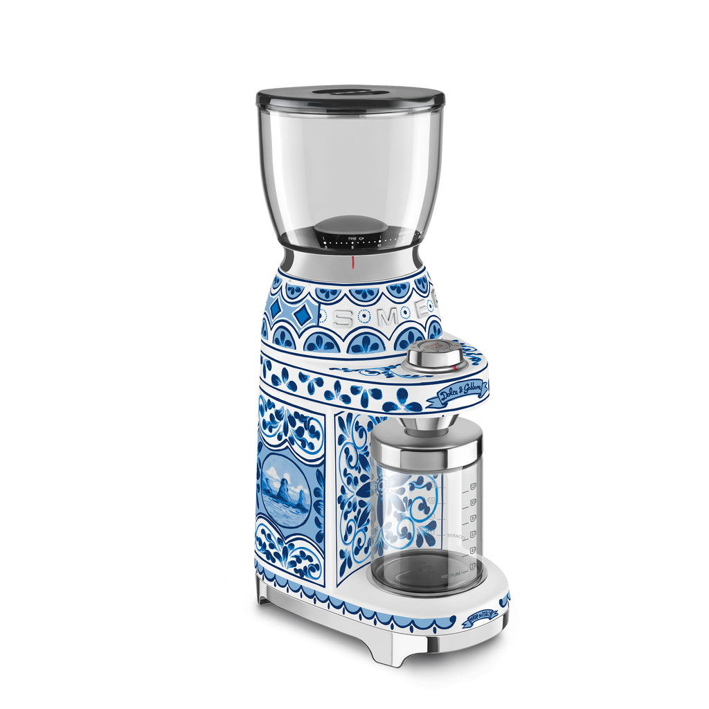 Smeg Dolce & Gabbana Blu Mediterraneo coffee grinder with sleek design and stainless steel finish, featuring a compact, modern look.