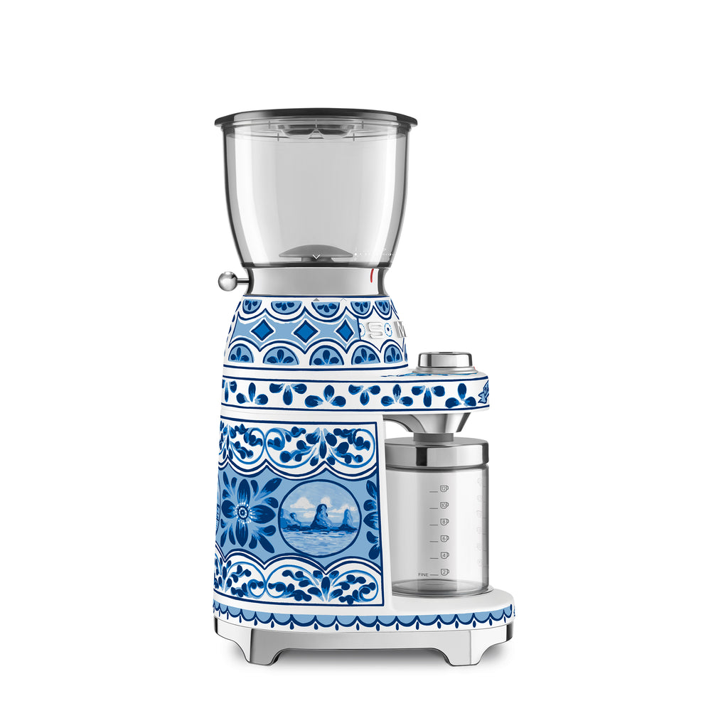 Smeg Dolce & Gabbana Blu Mediterraneo coffee grinder with sleek black and gold design, compact countertop appliance.