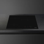 Smeg 60cm Ceran hob with four cooking zones and sleek black glass surface, installed in modern kitchen setting