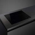 Smeg 60cm Ceran hob with four cooking zones and sleek black surface, installed in a modern kitchen setup.