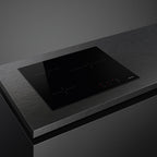 Smeg 60cm Ceran hob with four cooking zones and sleek black surface, installed in a modern kitchen setup.